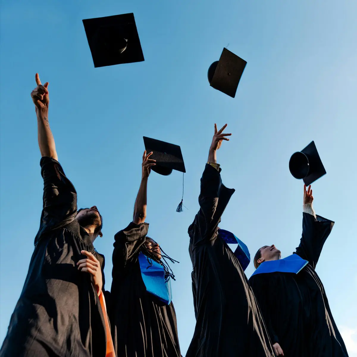 Photo of graduates throwing their caps in the air